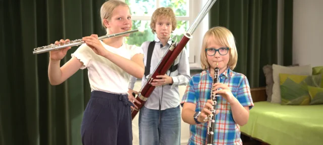 Bläserbande: Viele Kinder mit verschiedenen Blasinstrumenten in einem Halbkreis stehend