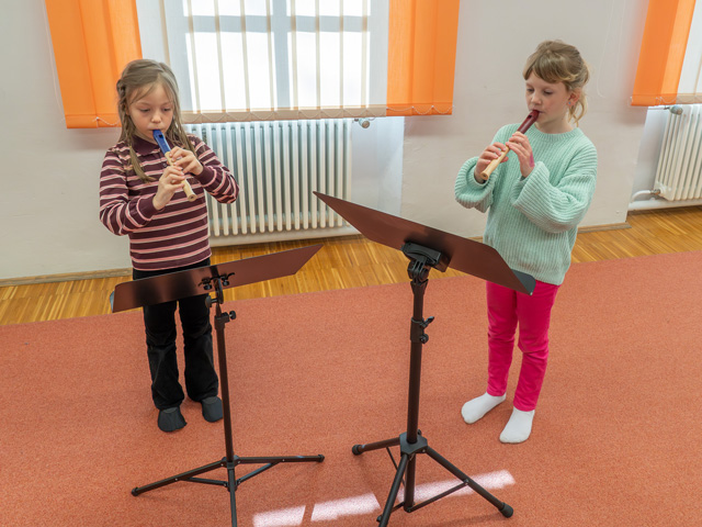 Zwei Mädchen spielen Blockflöte vor Notenständern