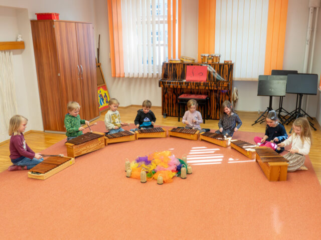 Kinder sitzen im Halbkreis mit Xylophonen vor sich stehend