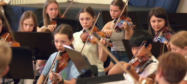 Viele Personen spielen verschiedene Instrumente - Vororchester