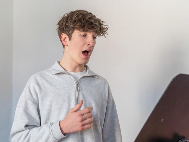 Gesang: Junge singt vor Notenständer