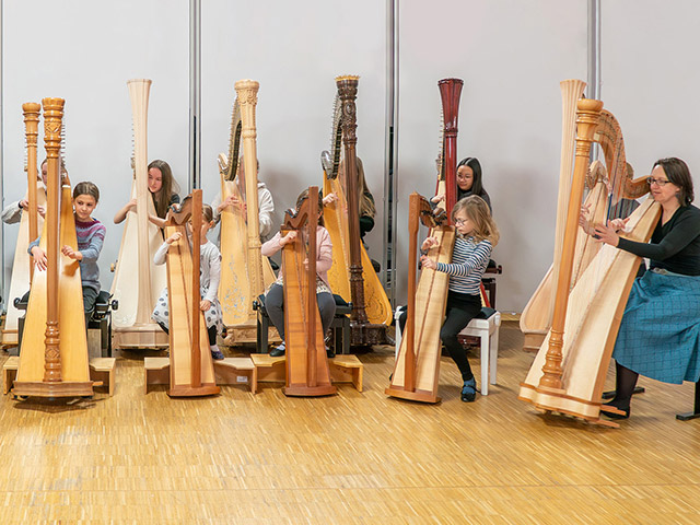 Viele Kinder und Musikschullehrerin spielen Harfe - Harfenorchester